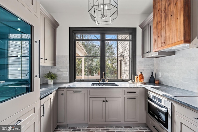 kitchen featuring oven, black electric stovetop, gray cabinets, and a sink