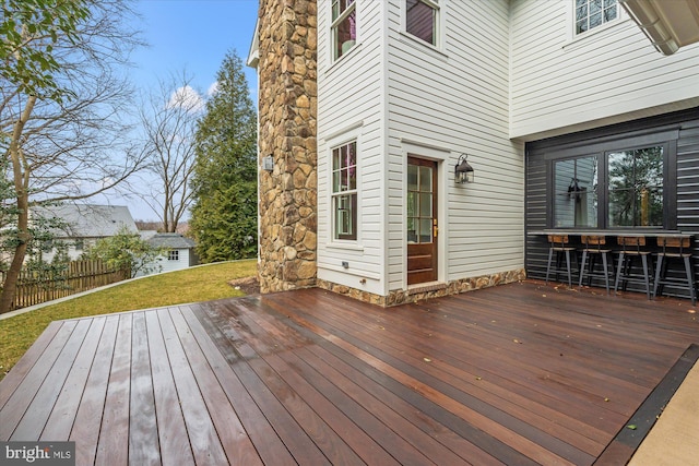 wooden deck featuring a lawn and fence