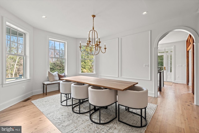 dining space featuring arched walkways, visible vents, breakfast area, and light wood-type flooring