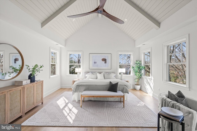 bedroom featuring beamed ceiling, multiple windows, and light wood finished floors