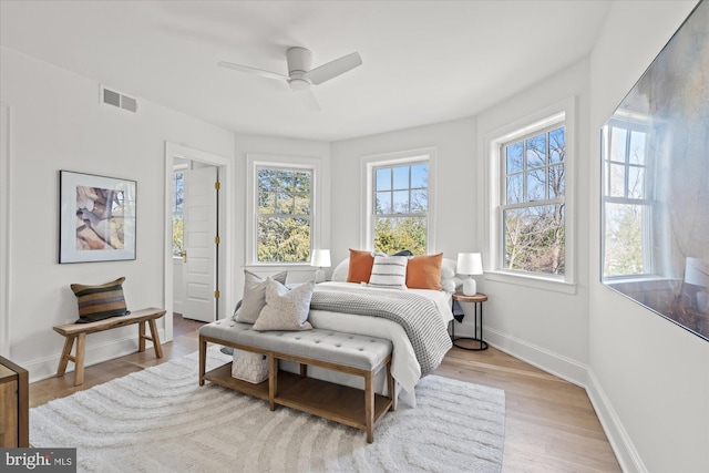 bedroom with ceiling fan, visible vents, baseboards, and wood finished floors