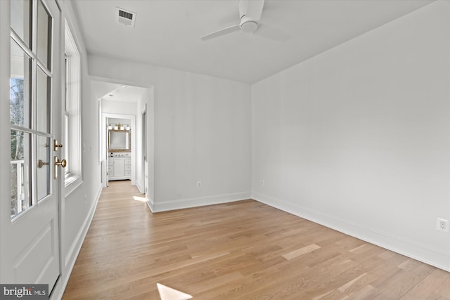 spare room featuring visible vents, ceiling fan, light wood-type flooring, and baseboards