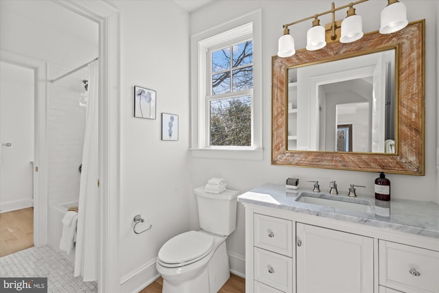 bathroom with vanity, toilet, wood finished floors, and baseboards