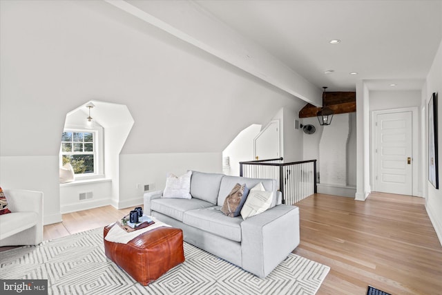 living area featuring lofted ceiling with beams, visible vents, baseboards, and wood finished floors