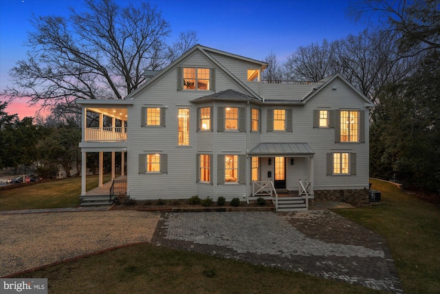 view of front of house featuring central air condition unit, covered porch, a front lawn, and a balcony