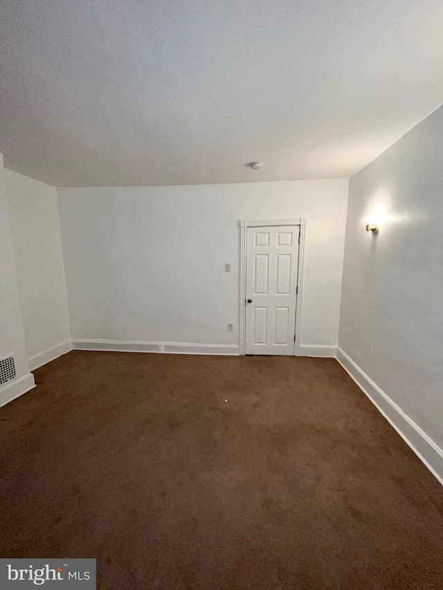 spare room with dark colored carpet