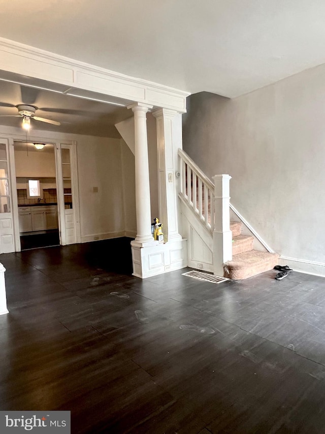 unfurnished living room with dark hardwood / wood-style flooring, decorative columns, and ceiling fan