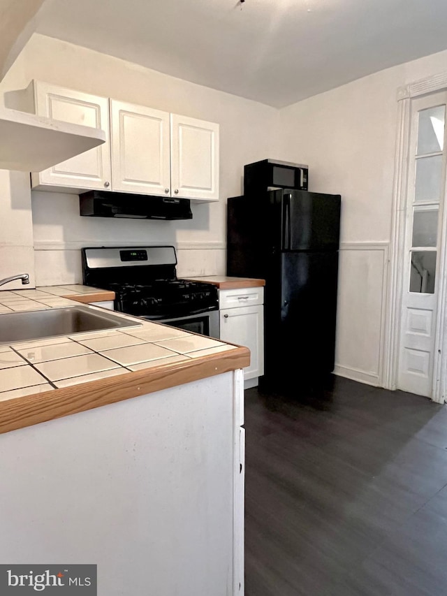 kitchen with white cabinetry, gas range, black fridge, and tile counters