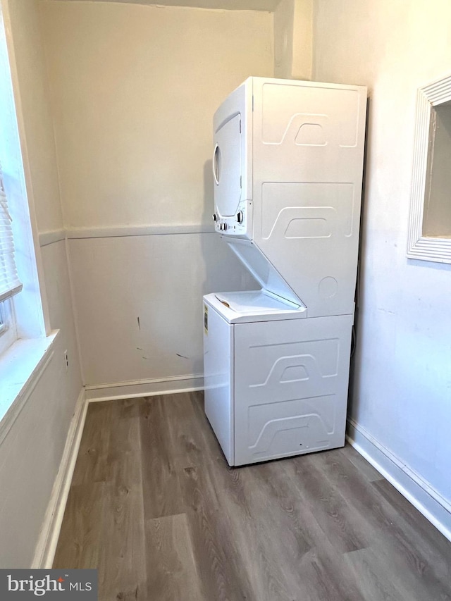 washroom with stacked washer and dryer and hardwood / wood-style flooring