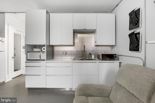 kitchen with tasteful backsplash, sink, white cabinets, and white appliances