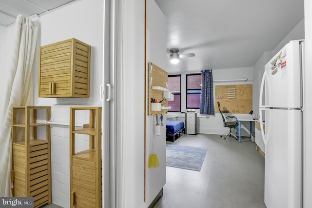 kitchen with concrete flooring, white fridge, and ceiling fan