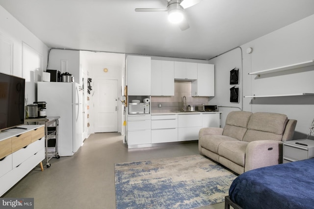 kitchen featuring sink, white cabinets, concrete floors, white refrigerator, and ceiling fan