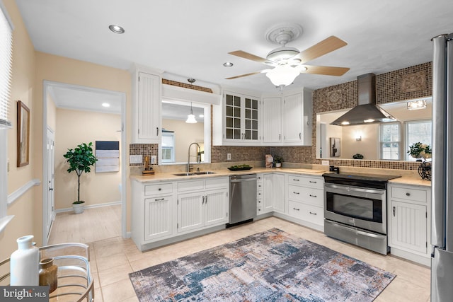 kitchen with wall chimney exhaust hood, sink, white cabinetry, appliances with stainless steel finishes, and pendant lighting