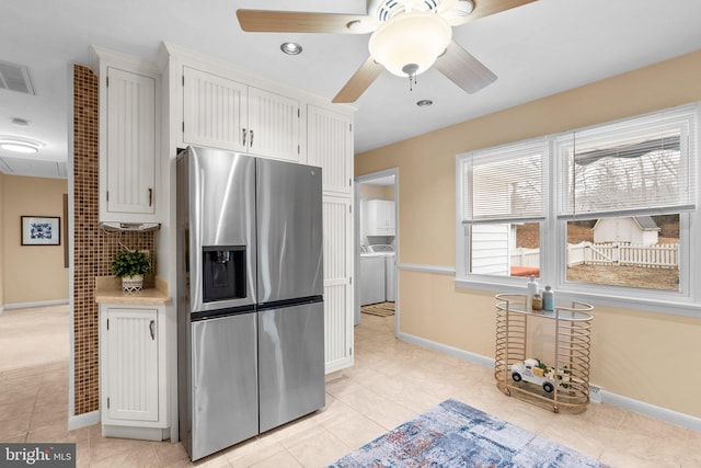 kitchen featuring light tile patterned flooring, washing machine and clothes dryer, white cabinets, and stainless steel fridge with ice dispenser