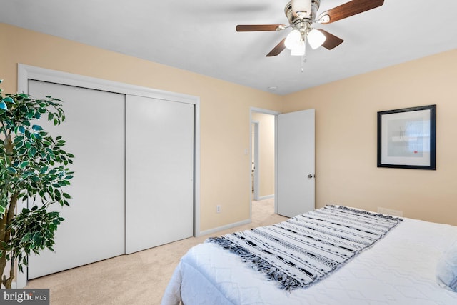 bedroom with light colored carpet, ceiling fan, and a closet