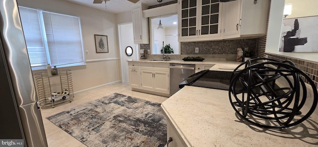 kitchen featuring decorative light fixtures, white cabinetry, decorative backsplash, ceiling fan, and stainless steel appliances