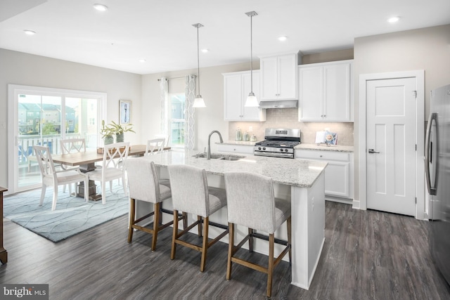 kitchen featuring pendant lighting, sink, appliances with stainless steel finishes, a kitchen island with sink, and white cabinets