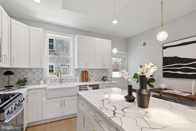 kitchen featuring light stone countertops, hanging light fixtures, and white cabinets