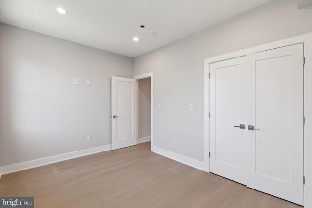 unfurnished bedroom with a closet and light wood-type flooring