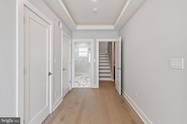 hall featuring a raised ceiling and light wood-type flooring