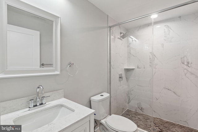 bathroom with vanity, tiled shower, and toilet