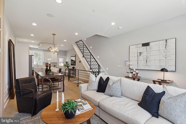 living room with sink, a chandelier, and light wood-type flooring