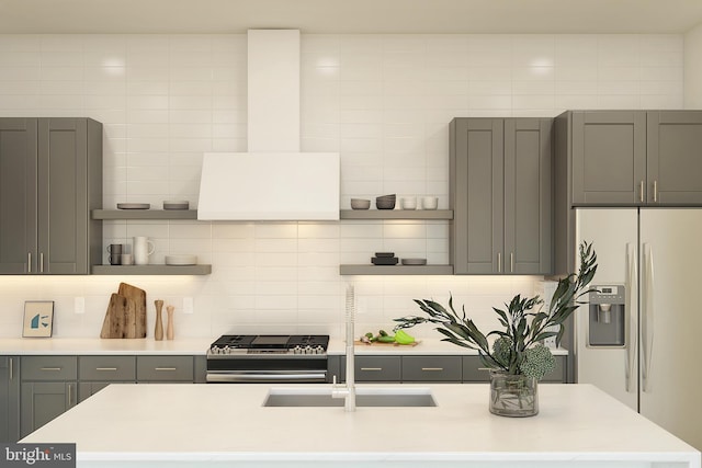 kitchen featuring gray cabinets, stainless steel stove, tasteful backsplash, white refrigerator with ice dispenser, and wall chimney range hood