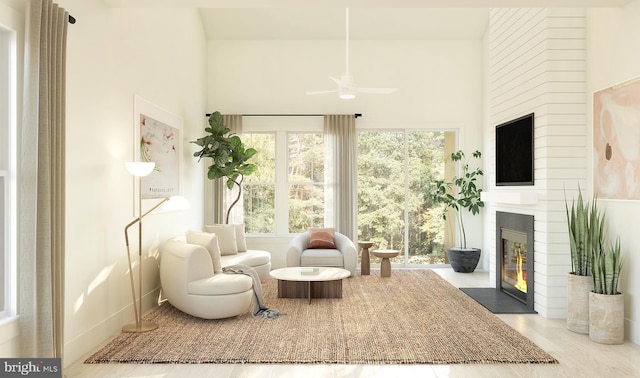 sitting room with a fireplace, ceiling fan, and light wood-type flooring