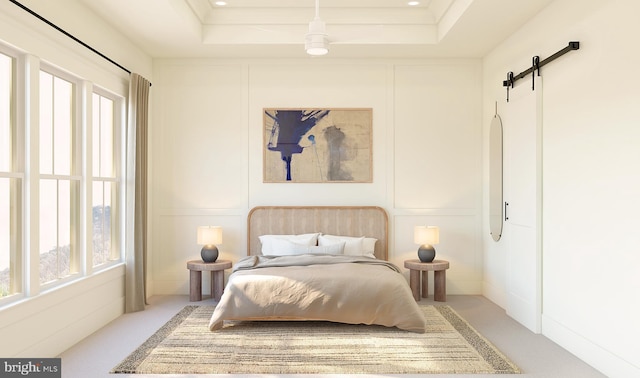 carpeted bedroom with a tray ceiling and a barn door