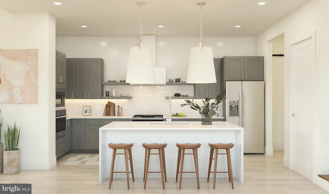 kitchen with gray cabinets, an island with sink, refrigerator with ice dispenser, pendant lighting, and oven