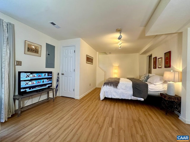 bedroom featuring electric panel and light wood-type flooring