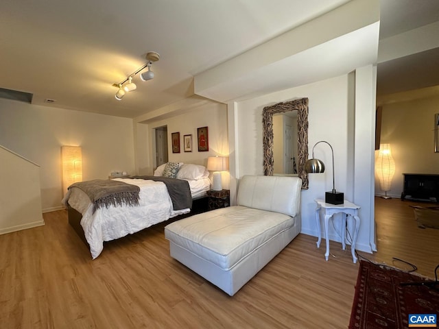 bedroom with hardwood / wood-style flooring and track lighting