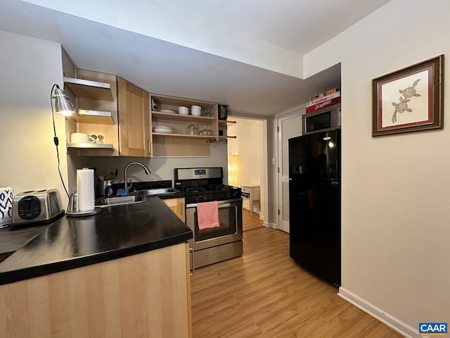 kitchen with stainless steel appliances, sink, light brown cabinetry, and light hardwood / wood-style flooring