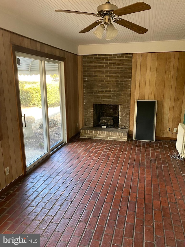 unfurnished living room with wooden ceiling, radiator heating unit, a fireplace, and wood walls