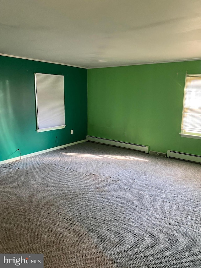 carpeted spare room with a baseboard heating unit