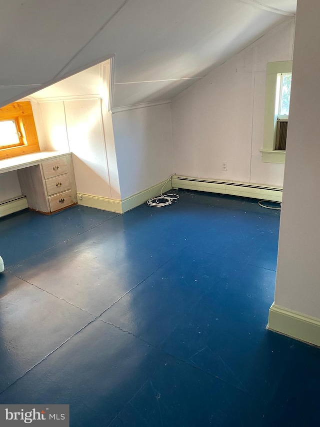 bonus room featuring baseboard heating, concrete flooring, built in desk, and vaulted ceiling