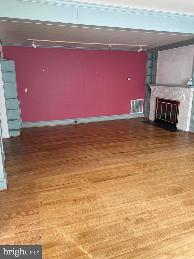 unfurnished living room with a brick fireplace and light hardwood / wood-style flooring