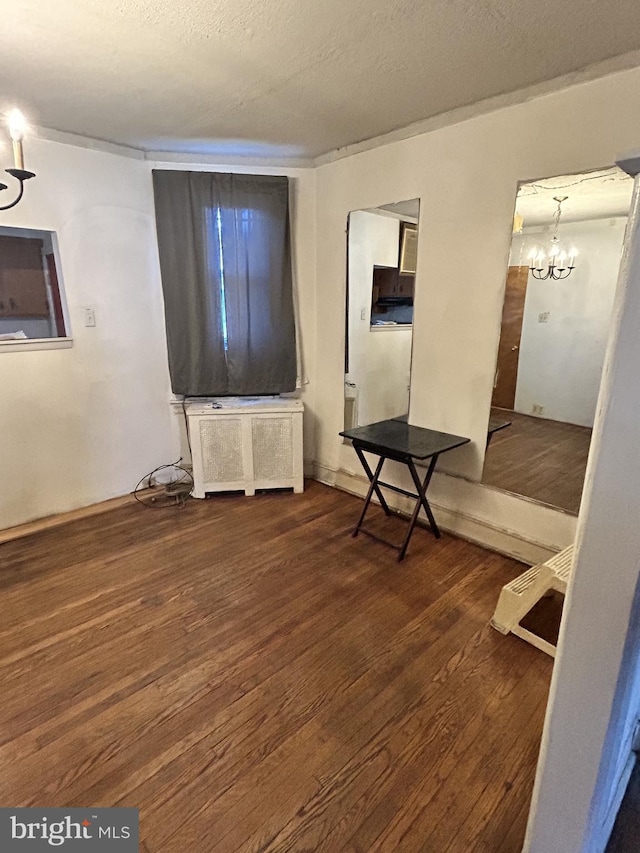 interior space featuring dark hardwood / wood-style flooring, radiator heating unit, a chandelier, and a textured ceiling