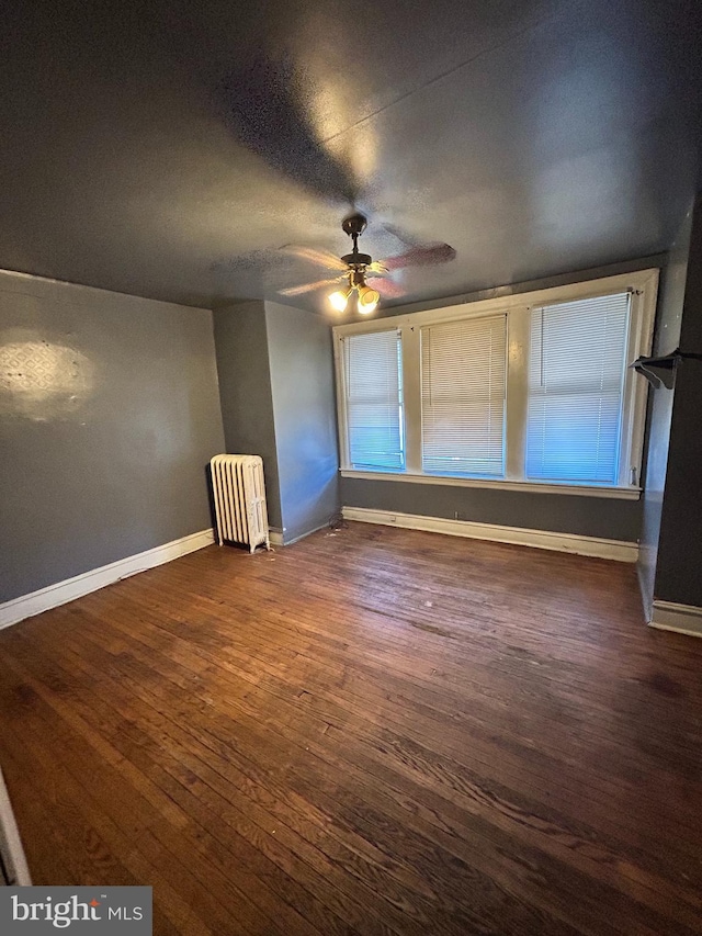 interior space with ceiling fan, radiator heating unit, and dark hardwood / wood-style floors