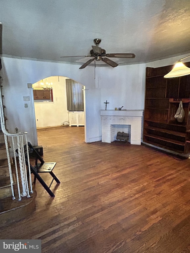 living room with ceiling fan, a fireplace, dark hardwood / wood-style flooring, and a textured ceiling