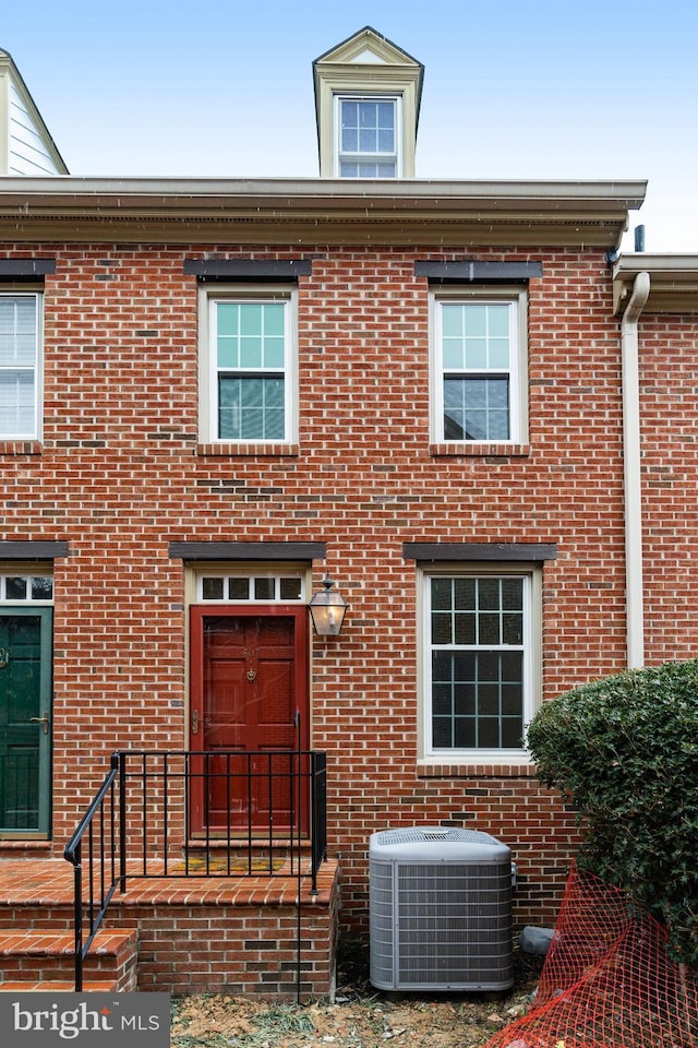 view of front facade featuring central AC and brick siding