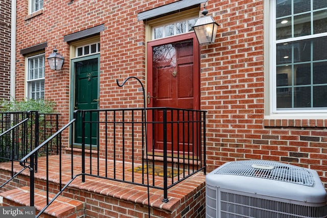 view of exterior entry featuring central air condition unit and brick siding