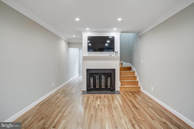 unfurnished living room featuring ornamental molding, a fireplace, and light hardwood / wood-style floors