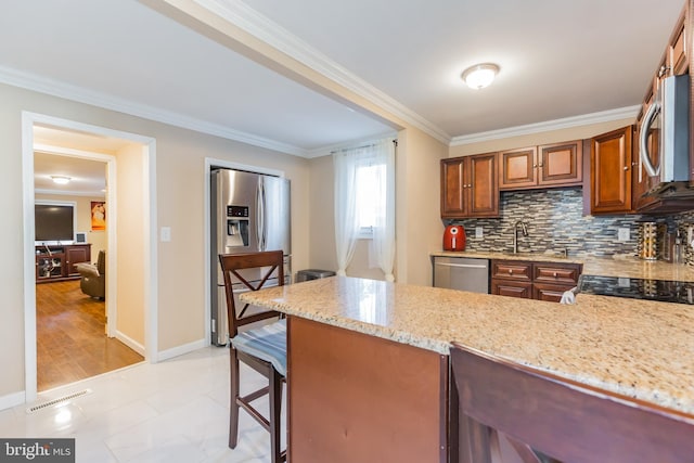 kitchen with appliances with stainless steel finishes, a kitchen bar, decorative backsplash, light stone counters, and crown molding