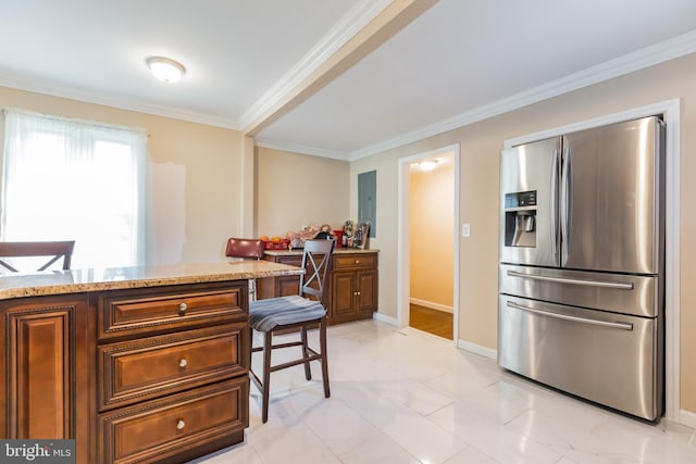 kitchen with stainless steel fridge, a breakfast bar area, built in desk, light stone countertops, and ornamental molding