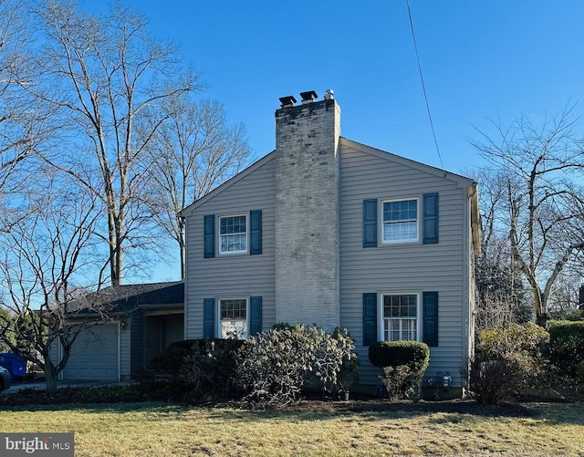 view of home's exterior with an attached garage, a yard, and a chimney