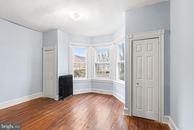 unfurnished room with radiator and dark wood-type flooring