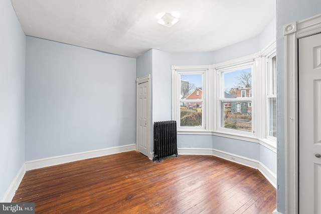 spare room featuring hardwood / wood-style floors and radiator heating unit