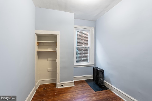 unfurnished bedroom featuring radiator and dark wood-type flooring