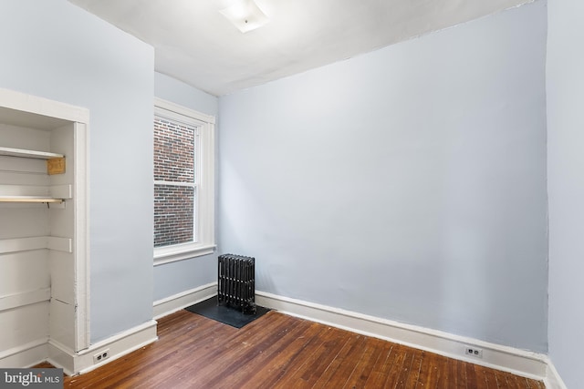 empty room featuring hardwood / wood-style flooring and radiator heating unit